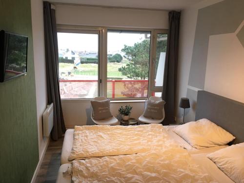 比伦Amelander Paradijs Ferienwohnung的卧室配有一张床和两把椅子,位于窗户前
