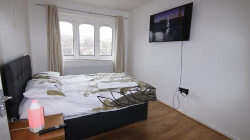 伯明翰3BED Maisonette Near CityCentre的卧室配有一张床,墙上配有电视。