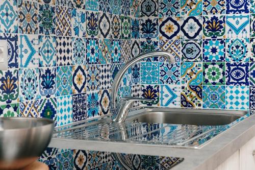 马里蒂玛Corte dei Fiori Acquaviva Apartments的厨房里设有水槽,铺有蓝色和白色的瓷砖