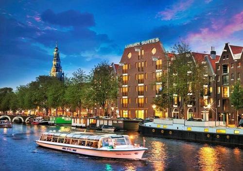 阿姆斯特丹Luxury Suites Amsterdam的船在建筑物前的河流中