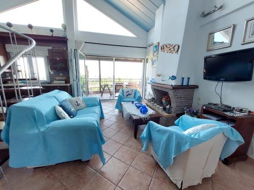 克里皮吉Grecia-Penisola Calcidica "My Romantic House Sea Wiew Terrace" Wi-Fi, BBQ, Garden,Parking的客厅配有蓝色的沙发和平面电视。