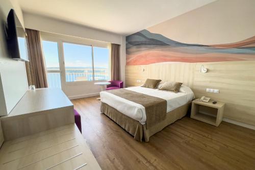 马盖鲁夫Bahia Principe Sunlight Coral Playa的酒店客房设有一张床,墙上挂有绘画作品
