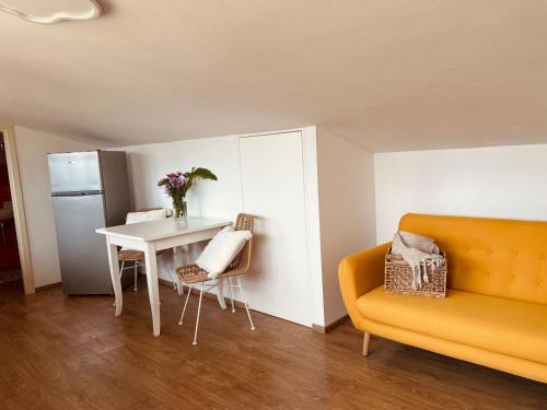 费拉约港La Mansarda degli Ulivi的客厅配有桌子和黄色沙发