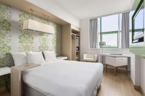 阿姆斯特丹阿姆斯特丹北NH酒店的卧室配有一张白色大床和一张书桌