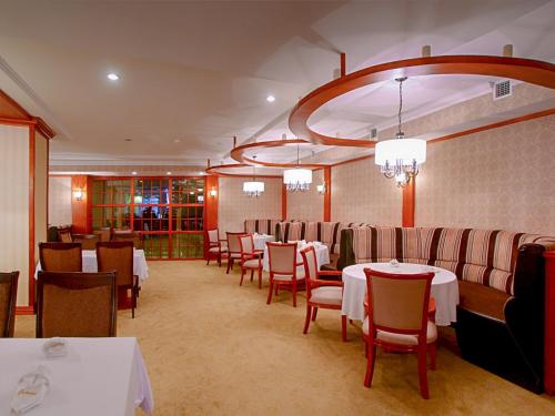 Darhan布黛酒店的餐厅配有白色的桌椅和吊灯