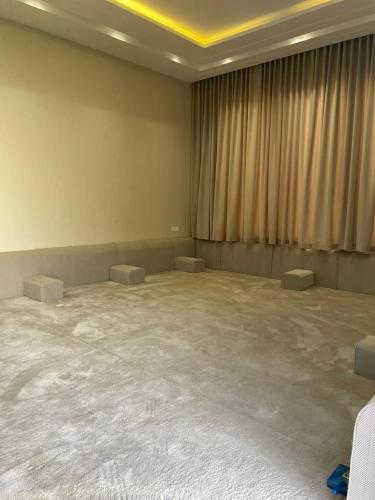 Bawḑahشالية الفهد的一间宽敞的空房间,配有两张桌子和窗帘