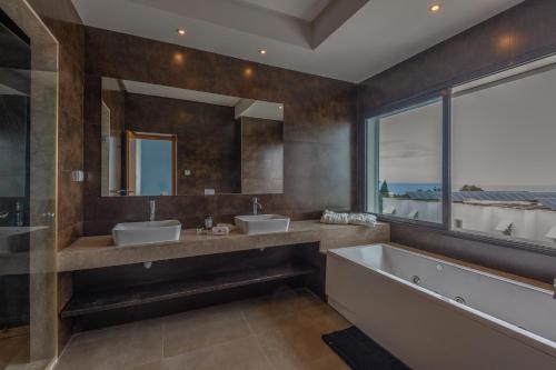 迦玛特Villa Lord Hammon的一间带两个盥洗盆和浴缸的浴室以及大窗户。