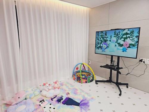 富川市Sosaeul Avenue kids room, family room的一间卧室配有一张带动物填充物的床和一台平面电视。