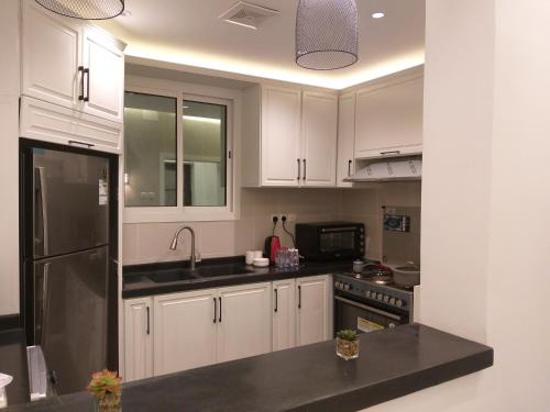 阿哈达فيلا الجبل的厨房配有白色橱柜和不锈钢冰箱