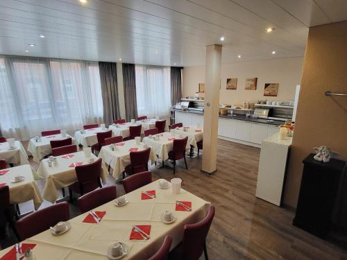 杜塞尔多夫阿斯科特康恩得酒店的一间带白色桌椅的餐厅和一间厨房