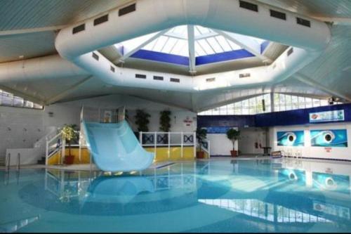 Lytchett MinsterRockley Park- Turlin Valley 36的一座大楼内带蓝色滑梯的游泳池