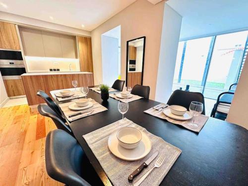 里斯本New Flat at Marques de Pombal的用餐室配有带椅子的黑色桌子和酒杯
