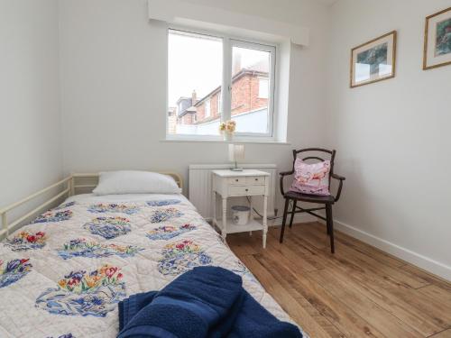 莱瑟姆-圣安妮14 Berwick Road的卧室配有床、椅子和窗户。