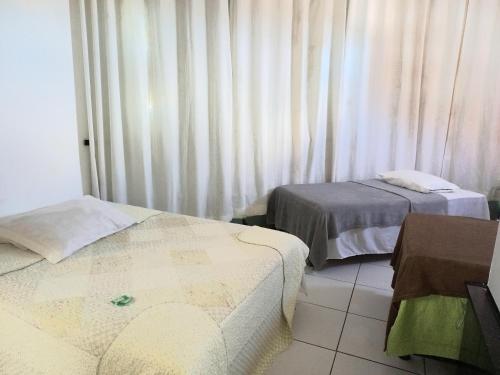 阿拉卡茹HOTEL AL MARE ATLANTICO的客房设有两张床和一个带窗帘的窗户。