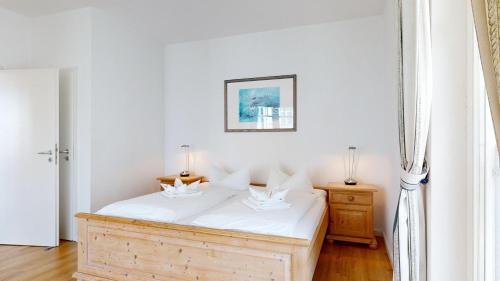宾茨Haus Saxonia的一间卧室配有一张带白色床单的木床