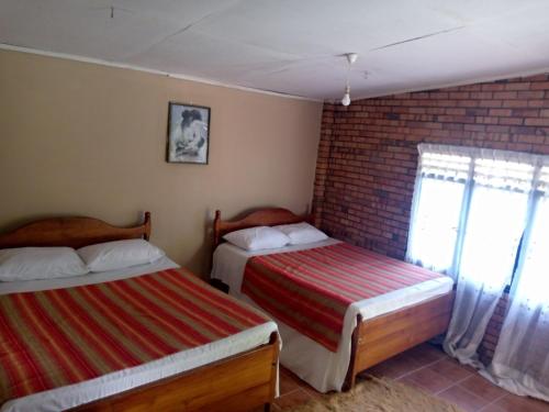 加姆波勒Maliga Inn的一间卧室设有两张床和砖墙