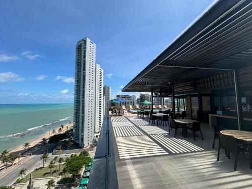 累西腓公园酒店的一座带桌椅的建筑,位于一个俯瞰着海滩的阳台