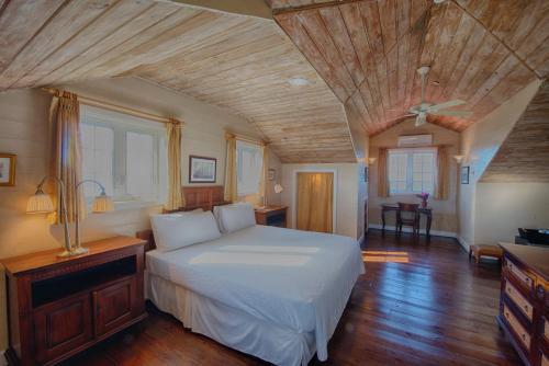 拿骚一箭之遥酒店的卧室设有白色的床和木制天花板。