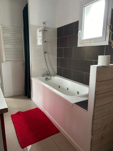 居让梅斯特拉Wilo Gujan的带浴缸的浴室,铺有红色地毯