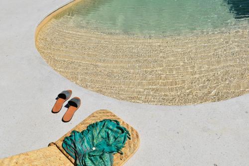 帕特莫斯Villa Alexandra的游泳池旁的一对人字拖和一篮子