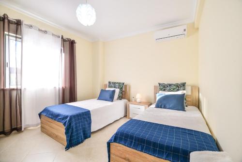 阿尔坎塔里利亚Vila com piscina a 5 minutos da Praia的一间卧室设有两张床和窗户。