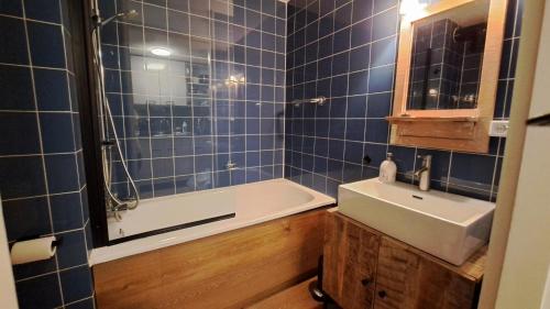 布勒伊尼瑟Appartement Bru Zeeland的浴室设有蓝色瓷砖墙壁、水槽和浴缸。