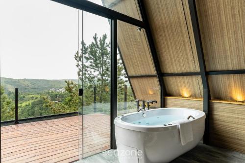 坎波斯杜若尔当Chales Naturale - Campos do Jordão - CNA的窗户前设有带浴缸的浴室