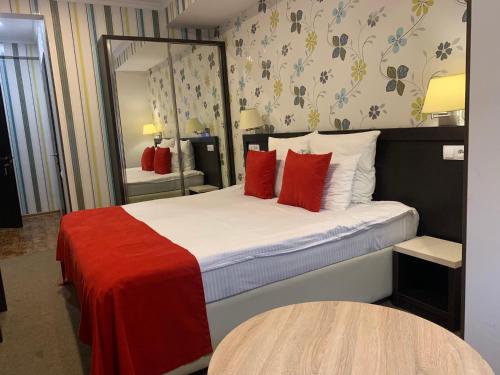 第比利斯East Gate Boutique Hotel的一间卧室配有一张带红色枕头和镜子的床