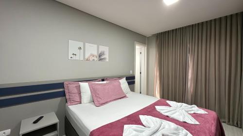 库里提巴14- Studio decorado com ótima localização!!!的一间卧室配有一张粉色和白色床单。