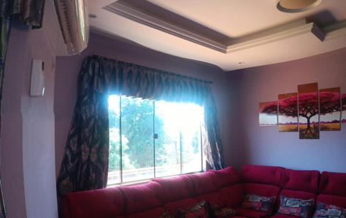 埃斯特城Ñande renda的客厅里的一个红色沙发,带有窗户