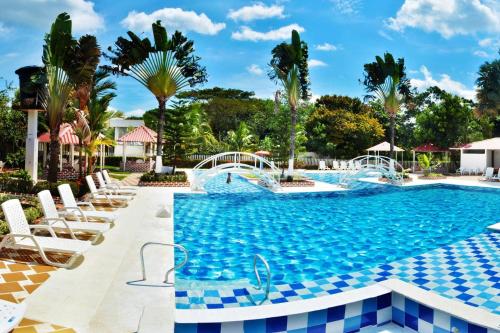AguazulCENTRO VACACIONAL & HOTEL CAMPESTRE LAGO CENTER的一个带椅子和树木的度假村游泳池