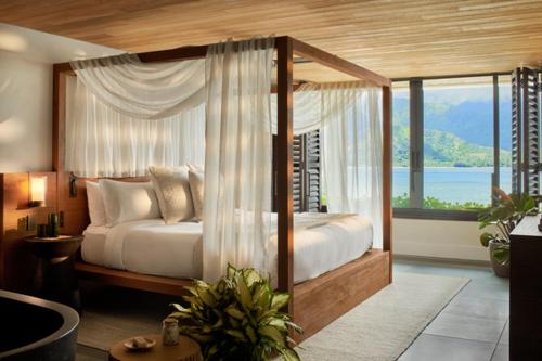 普林斯维尔1 Hotel Hanalei Bay的一间卧室设有一张天蓬床,享有海景
