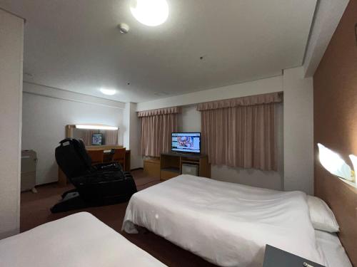 鸟取市Hotel Alpha-One Tottori的酒店客房配有一张床、一把椅子和一台电视。