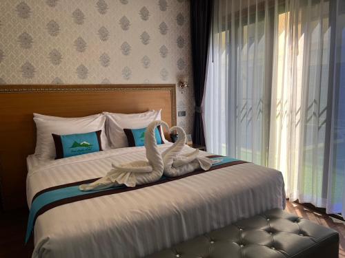 Khao YaiBaan Plaifah Khao Yai Hotel的一间卧室,卧室配有两只用毛巾制成的天鹅,床边配有毛巾