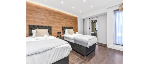 伦敦Luxury Abode: 5-Bed Haven Ideal for Big Groups!的酒店客房设有两张床和窗户。