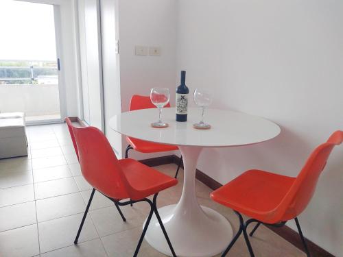 拉普拉塔Hermoso Departamento Unico的一张带两个酒杯的白色桌子和红椅子