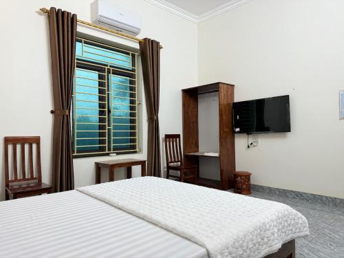 Nho QuanHotel Minh Thắng的一间卧室设有一张床、一台电视和一个窗口。