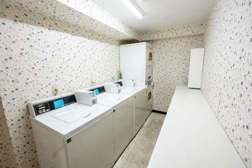甲府ユースホステルソノママ的厨房配有白色橱柜和白色冰箱。