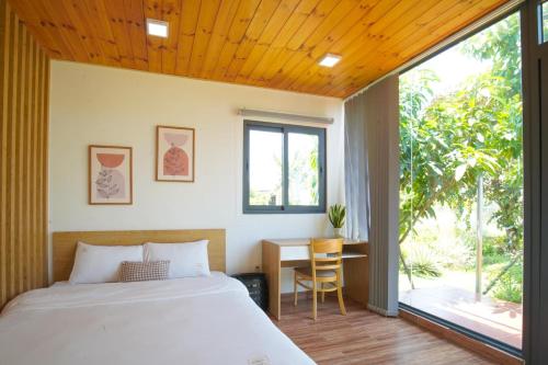 Long AnHana Villa Long An的一间卧室配有一张床、一张书桌和一个窗户。