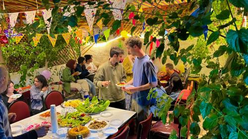 亚喀巴Al-Amer Hostel 1的一群人站在桌子旁吃着食物