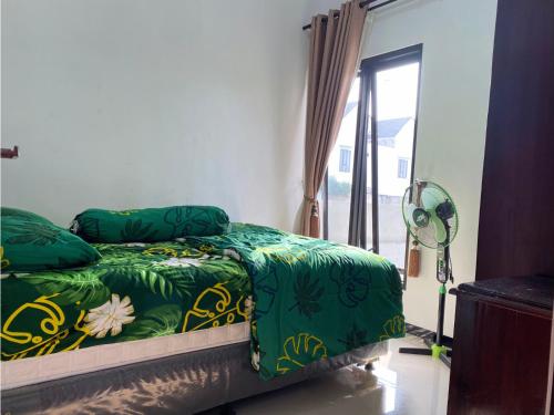 玛琅Villa Harga Terjangkau di Malang的一间卧室配有一张带绿色床单的床和一扇窗户。