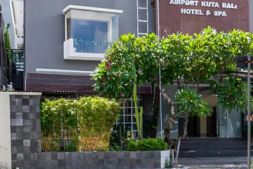 库塔Super OYO 93765 Airport Kuta Bali Hotel的前面有树木和灌木的建筑