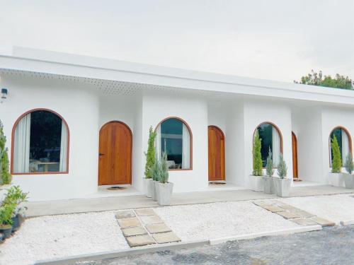 Ban Sao ThongRamida House บ้านรมิดา的白色的房子,有木门和盆栽植物