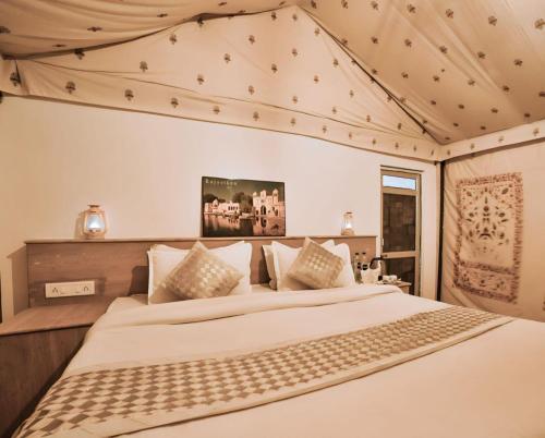 斋沙默尔Griat sandy desert camp jaisalmer的卧室配有一张带白色床单和枕头的大床。