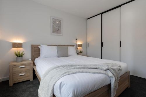 Franklin VillageHome sweet home with secure parking的卧室配有一张白色的大床和床头柜。