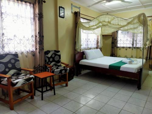 蒙巴萨Cs Apartment Mombasa Mtwapa的一间卧室配有一张床和一把椅子