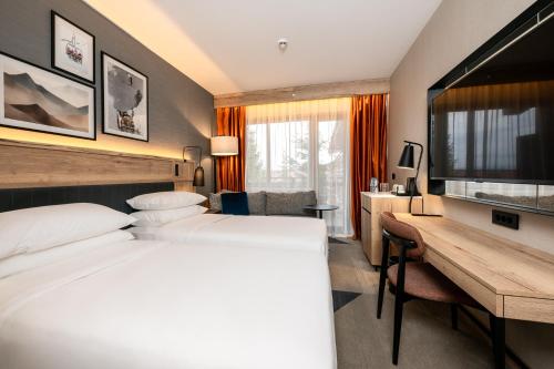 班斯科Four Points by Sheraton Bansko的酒店客房配有两张床和一张书桌