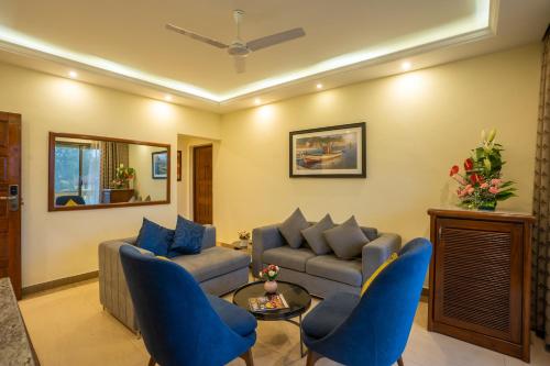 坎多林De Mandarin Beach Resort Suites & Villas, Candolim的客厅配有蓝色椅子和沙发