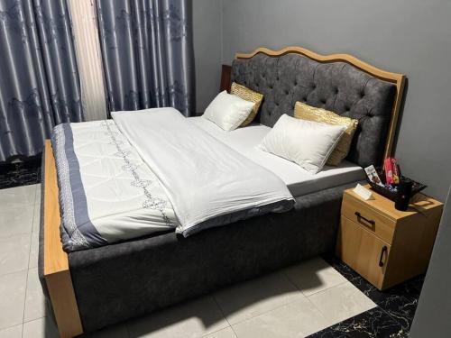 鲁亨盖里2 bedroom apartment in Musanze( Benji)的一张带黑色床头板、白色床单和枕头的床