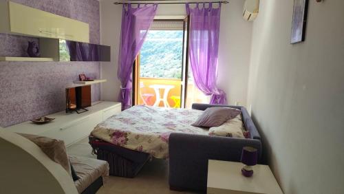 Isola del GiglioIsola del Giglio casa Nico e casa Camilla Monticello Giglio Porto的一间卧室配有一张床和一个带紫色窗帘的窗户